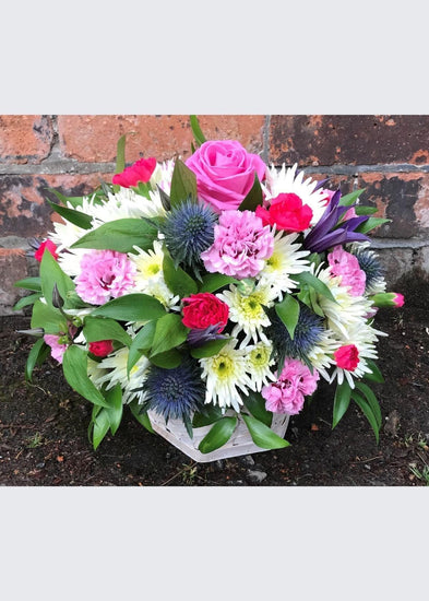 This pretty white, pink and purple arrangement is made up of Roses, Lisianthus, Veronica, Chrysanthemums Carnations and seasonal flowers and foliage. This arrangement in a basket. This makes an excellent gift for a new Mum, someone who is ill or someone who has just moved into their new home who needs a ready made arrangement are in floral foam which is easy to care for.
