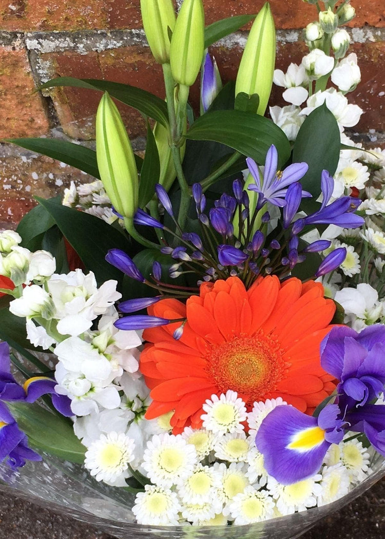 Anne Radcliffe Hand Tied Bouquet. This vibrant bouquet beautifully combines orange, white and purple flowers to make a simple and stylish gift. It portrays Anne Radcliffe's vivid descriptions of lush landscapes and long travel scenes. Perfect for a birthday or anniversary celebration.