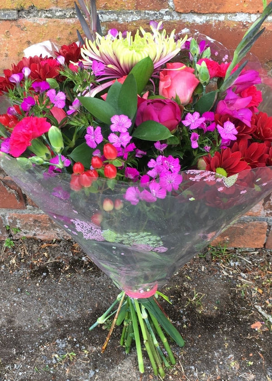 Brocade Hand Tied Bouquet in an Aquapack. This popular red and pink Hand Tied bouquet includes Roses, Chrysanthemums and Carnations with season flowers and foliages. A very cheerful birthday or Get Well Soon gift.