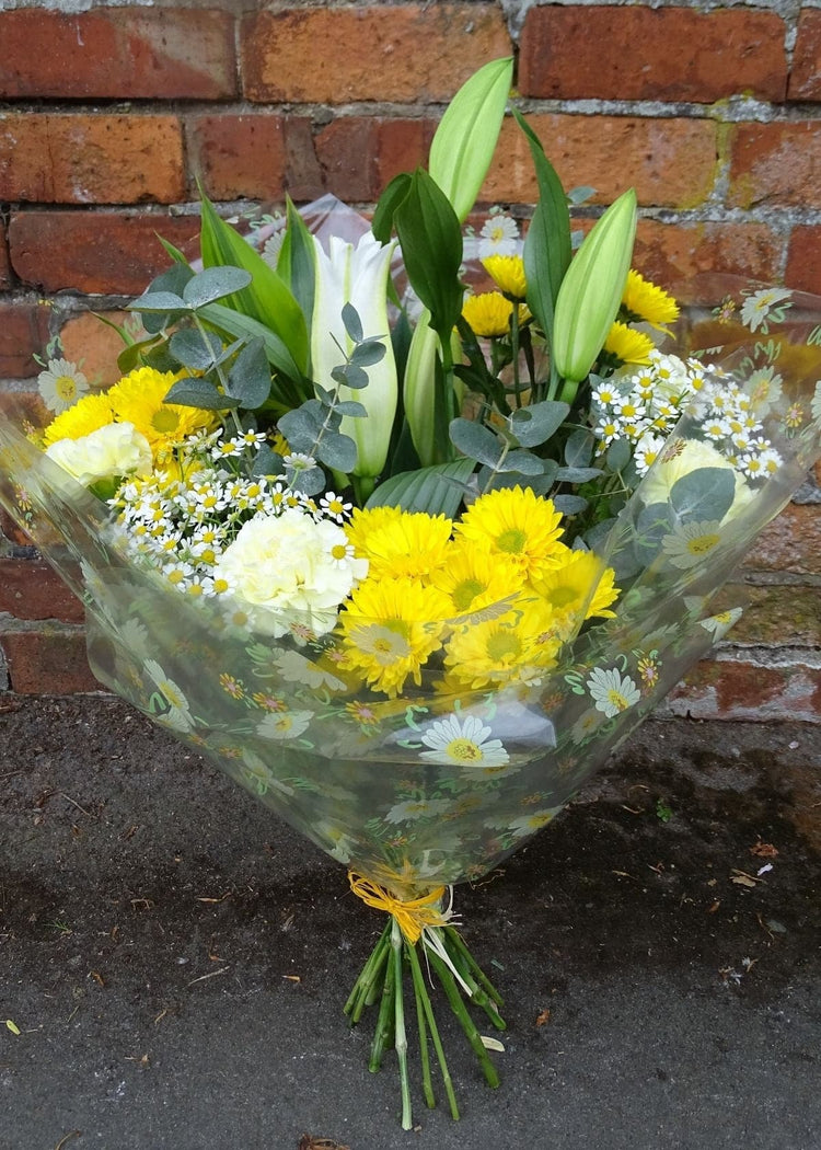 Chamomile Hand Tied Bouquet. This fresh, zesty bouquet beautifully combines yellow and white flowers to make a simple and stylish gift. It includes a white Lily, Carnations, Chrysanthemums, with seasonal flowers. A beautiful anniversary, birthday or Just to Say... gift.