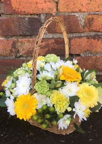 Charlotte Bronte Flower Basket. A fabulous trug basket, filled with yellow Ranunculi, Solidago, Lisianthus, Alstroemeria and white Chrysanthemums and seasonal flowers and foliages. This basket arrangement makes an ideal Spring gift for any occasion as it is a ready made arrangement in floral foam which is easy to care for.