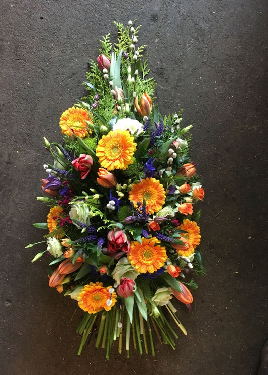 This funeral sheaf of country garden flowers and grasses is made in floral foam to prolong the life of the blooms. It is bursting with cheerful orange, purple and white flowers including Germini, Veronica, Lisianthus and other seasonal flowers and foliage.