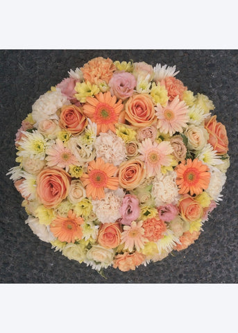 This compact funeral posy by Make Their Day florist is created from pastel shades of mini Gerberas, Roses, spray Roses, Chrysanthemums and Lisianthus. This tribute may be made in any colour combination. Please select your preference.  This funeral tribute is 12