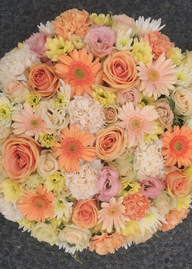 This compact funeral posy by Make Their Day florist is created from pastel shades of mini Gerberas, Roses, spray Roses, Chrysanthemums and Lisianthus. This tribute may be made in any colour combination. Please select your preference.  This funeral tribute is 12" (30cm) approx. diameter and is most suitable from a family member or a close friend to a lady or gentleman of any age.