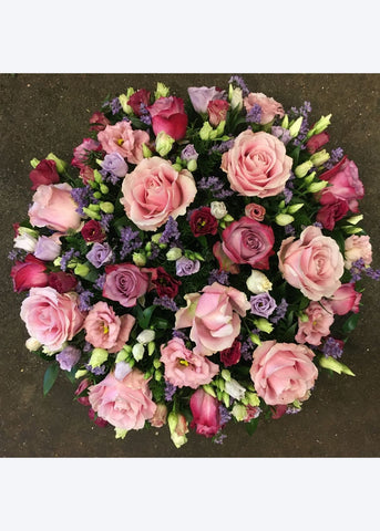This domed funeral posy is created from pink Roses and Lisianthus interspersed with seasonal flowers and foliages.
