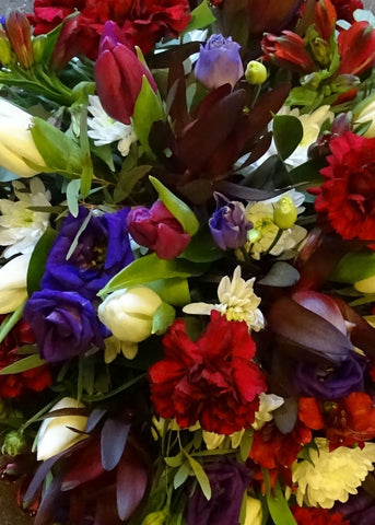 This funeral casket spray is a loose, single ended teardrop shape, fashioned from rich red and purple tones by Make Their Day florist.  If there is a favourite flower that you would like included, we will do our best to supply it. Please call or visit us to place your order. We will let you know if a specific flower will incur an additional cost when we take your order.