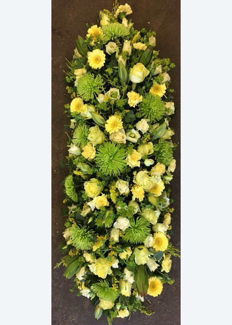A zesty family funeral tribute of green and yellow seasonal flowers including Roses, Chrysanthemum Blooms, Carnations, Germinis and other seasonal flowers and foliage.