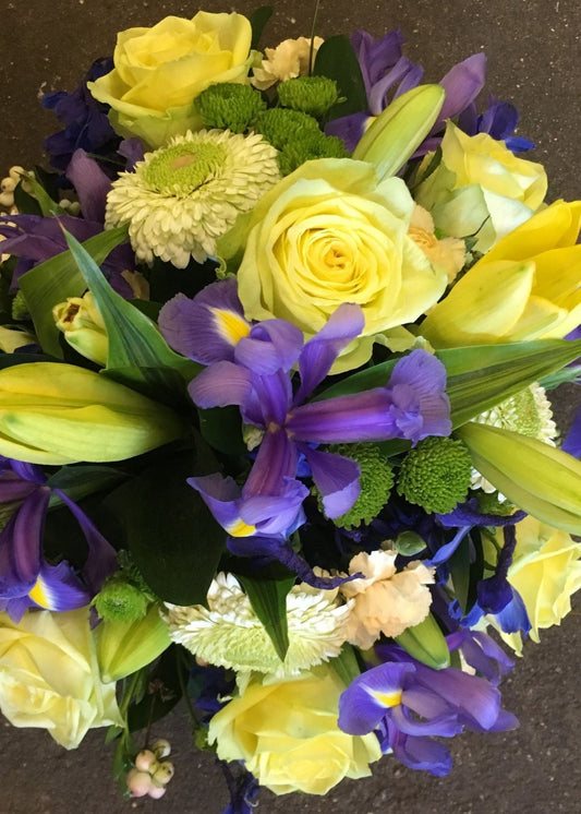 A bright posy funeral tribute of yellow and blue flowers by Make Their Day florist. It includes Roses, Chrysanthemums and Irises and other seasonal flowers and foliage.  The standard price is for an 14" (36cm) posy and is suitable from a family member, friend, work colleague or neighbour for a lady or gentleman.
